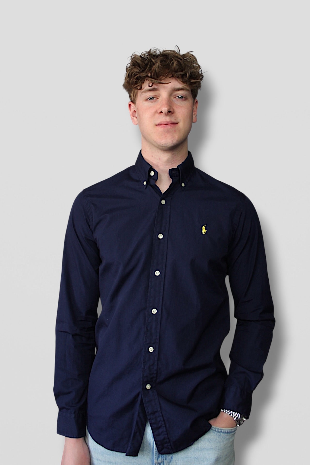 Man wearing a navy blue shirt with a logo on a light gray background