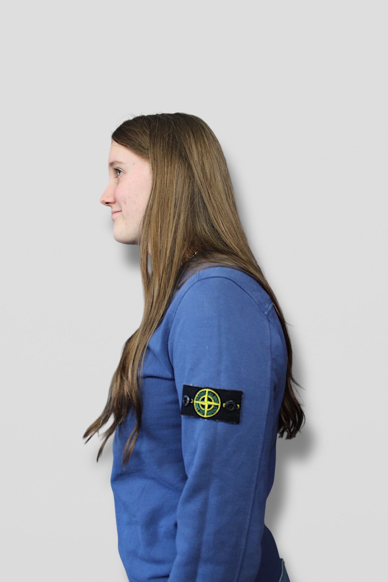 Person wearing a blue jacket with a visible brand logo on a light gray background