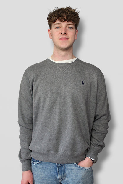 Person wearing a gray sweatshirt with a logo on a plain background