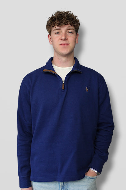 Man wearing a blue pullover with a logo on a light gray background