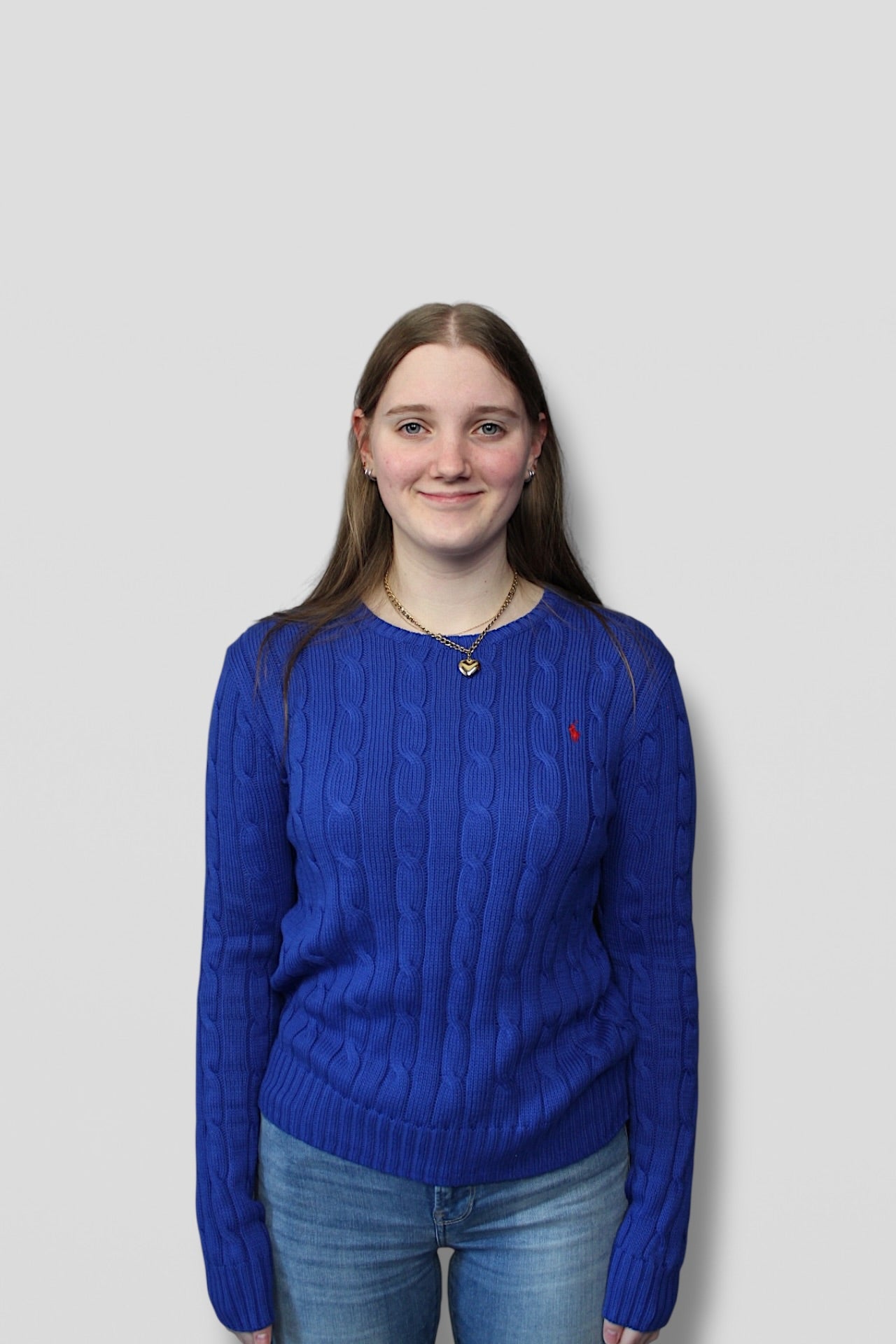 Person wearing a blue sweater with a brand logo on a plain background